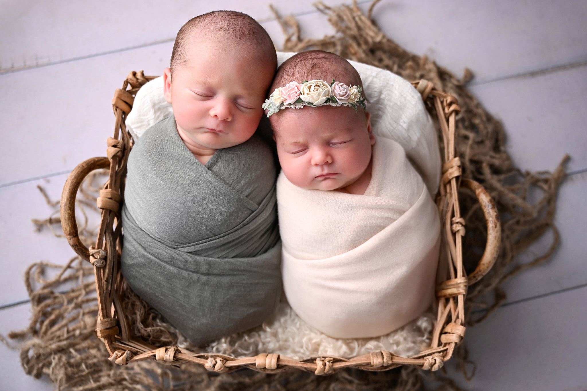 Twins newborns in a handmade basket posed together